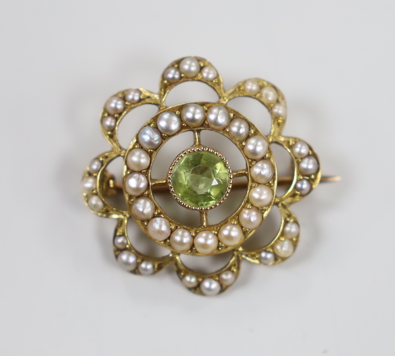 A late Victorian 15ct peridot and seed pearl set cluster brooch, 21mm, gross weight 3 grams.